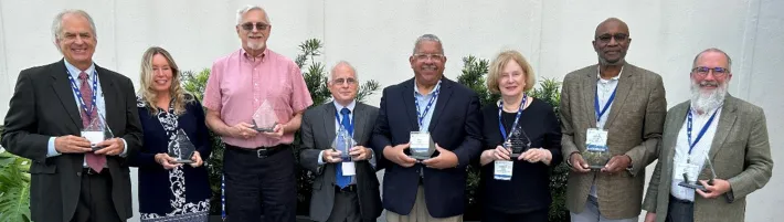 NCSC award recipients holding trophies outdoors smiling.