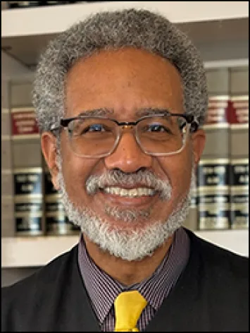 Smiling man with glasses in front of bookshelves