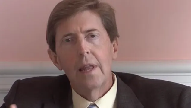 Man in suit speaking, neutral background