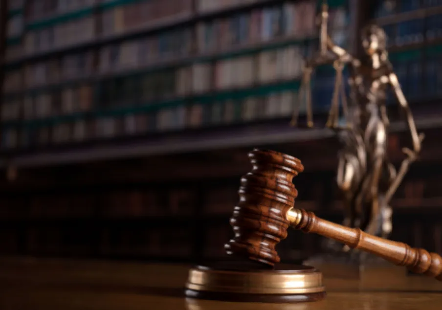 Wooden judge gavel and scales in courtroom library